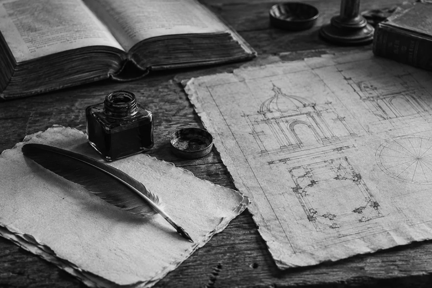 Раскрытая книга, перо, чернильница и архитектурный чертёж на столе
